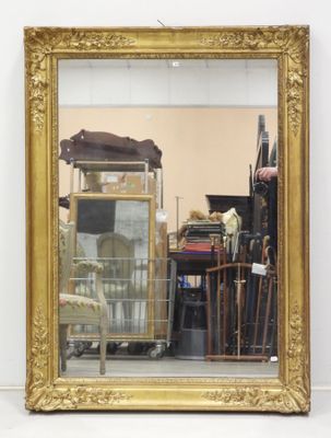 a gold framed mirror sitting on the floor in front of a chair