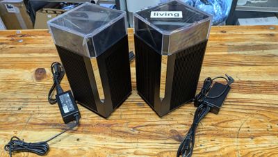 deux enceintes posées sur une table en bois, avec un chargeur