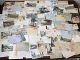 de nombreuses cartes postales anciennes posées sur une table, avec une chaise en arrière-plan