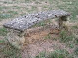 un banc en pierre au milieu d'un champ herbeux