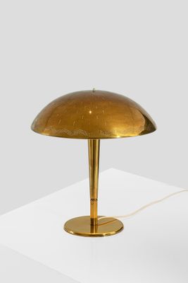 a gold table lamp on a white surface with a white background
