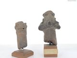 two stone figurines of a man and a woman on a wooden stand