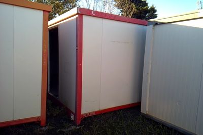 three white and red storage containers in the grass