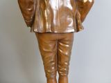 bronze statue of a man in a suit and tie with his hands on his hips