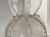 a clear glass bottle with a handle on a table