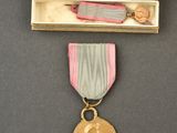 une médaille dans un coffret en bois, accompagnée d'un ruban et contenant un ruban