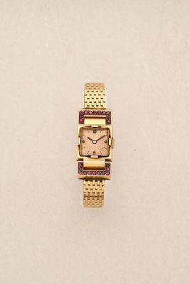 an image of a gold wrist watch with a pink face