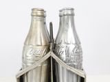 two coke bottles in a metal holder on a table