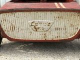 an old rusted red and white car parked in a parking lot
