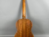 une guitare en bois posée sur un support, sur fond gris