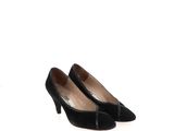 Les chaussures noires de la femme reposent sur la surface blanche.