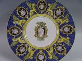 une assiette bleue et jaune sur laquelle est représentée une femme