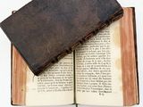 an old book that is open on a white surface