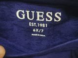 guess logo on a t - shirt that is being held by a person