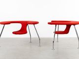 two red chairs and a table in a room with a white wall