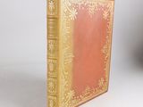 a red book with gold trim sitting on a white surface