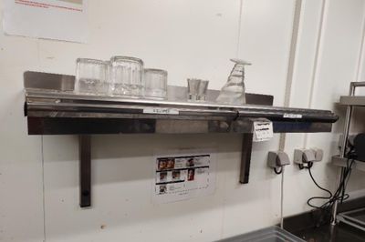 a metal shelf with glasses on it in a kitchen