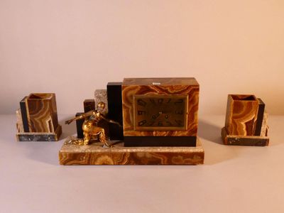 une petite horloge posée sur une table, à côté d'autres objets