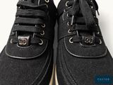black sneakers with white soles on a white surface