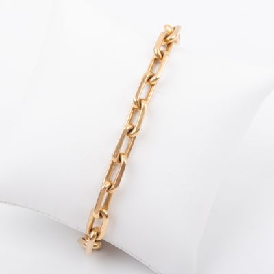 a close up of a gold bracelet on a white pillow