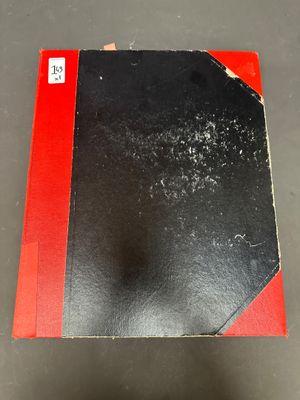 une image représentant un livre noir et rouge posé sur une table