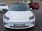 a white tesla model 3 parked in a parking lot