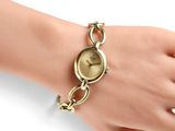 an image of a woman ' s wrist with a gold watch on it