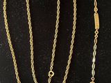 two gold necklaces and a ring on a black surface