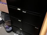 a black filing cabinet in the corner of a room with boxes on the floor