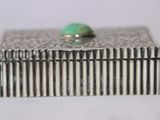 a silver box with a green stone on top of it