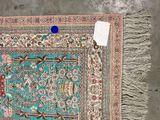 an oriental rug with a blue border and fringes on a gray floor