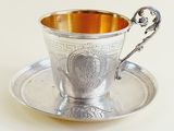 a silver cup and saucer sitting on a saucer