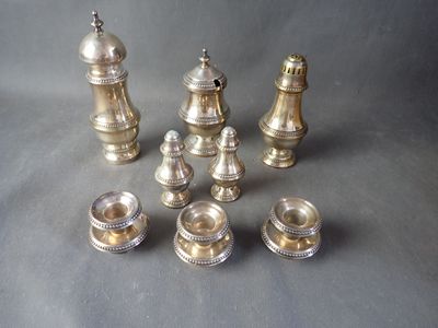 several pieces of silver metal chess pieces on a gray surface