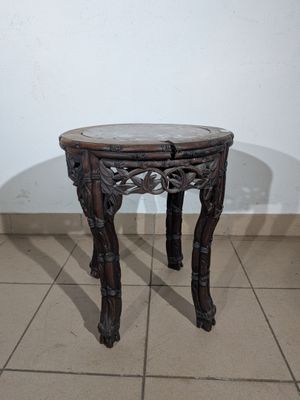 a small wooden table with a glass top on a tiled floor