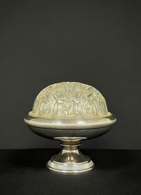 un plat ancien en argent avec un couvercle bombé, posé sur un socle
