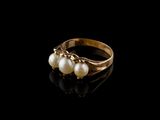 un gros plan d'une bague en or ornée de perles sur un fond noir