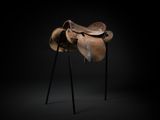 a horse saddle on a stand against a black background