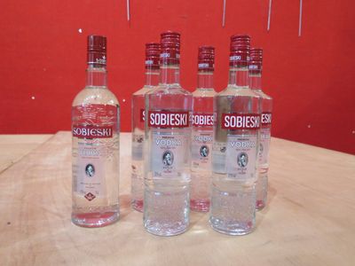 quatre bouteilles de vodka posées sur une table devant un fond rouge
