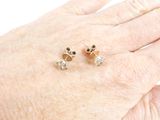 a woman ' s hand holding a pair of gold and diamond stud earrings