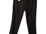 Le pantalon noir est suspendu à un cintre accroché à un mur blanc.