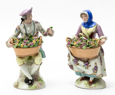 two figurines of women with baskets of flowers on their heads