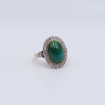 gros plan d'une bague avec une pierre verte entourée de diamants