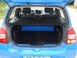 the back of a blue car with its trunk open on a gravel road