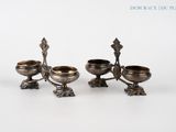 three silver plated candlesticks on stands on a white surface