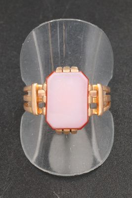 pink glass ring with gold accents on a clear acrylic stand
