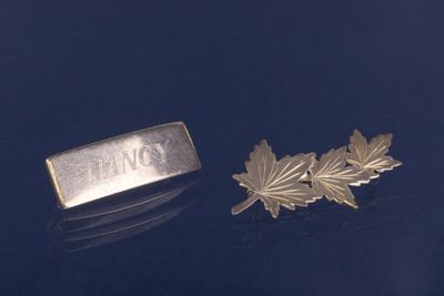 broche plaquée argent ornée d'une feuille et d'une plaque portant un nom