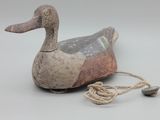 un petit canard en bois auquel est attachée une corde