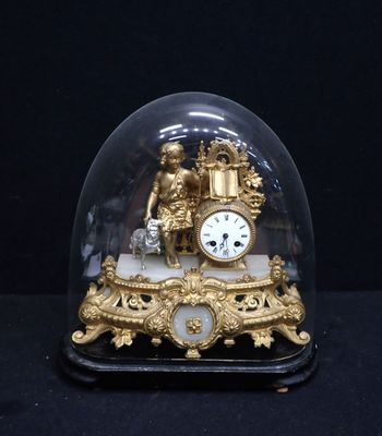 a gold clock under a glass dome on a black surface
