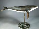 statue of a humpback whale on a stand on a gray background