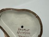 a hand holding a small ceramic object with writing on it